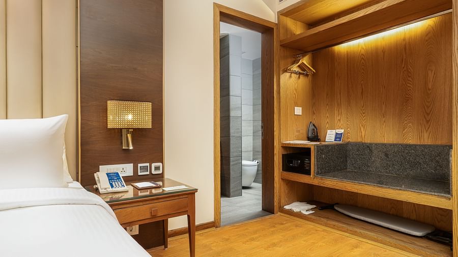 Warm-toned bedroom with a double bed, a nightstand, a wardrobe, and sophisticated design - Sarovar Premiere, Srinagar